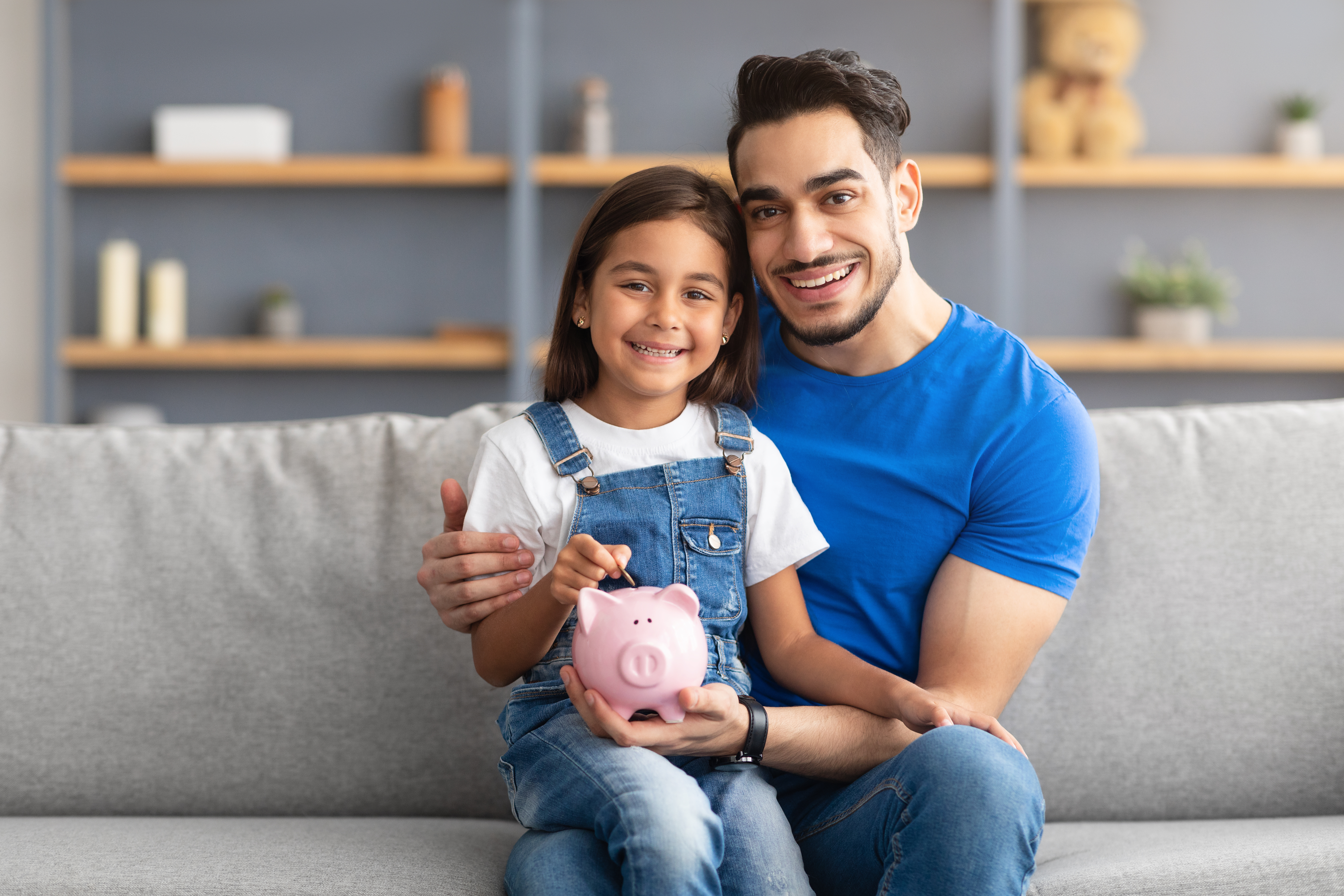 Little girl and dad saving money in piggy bank